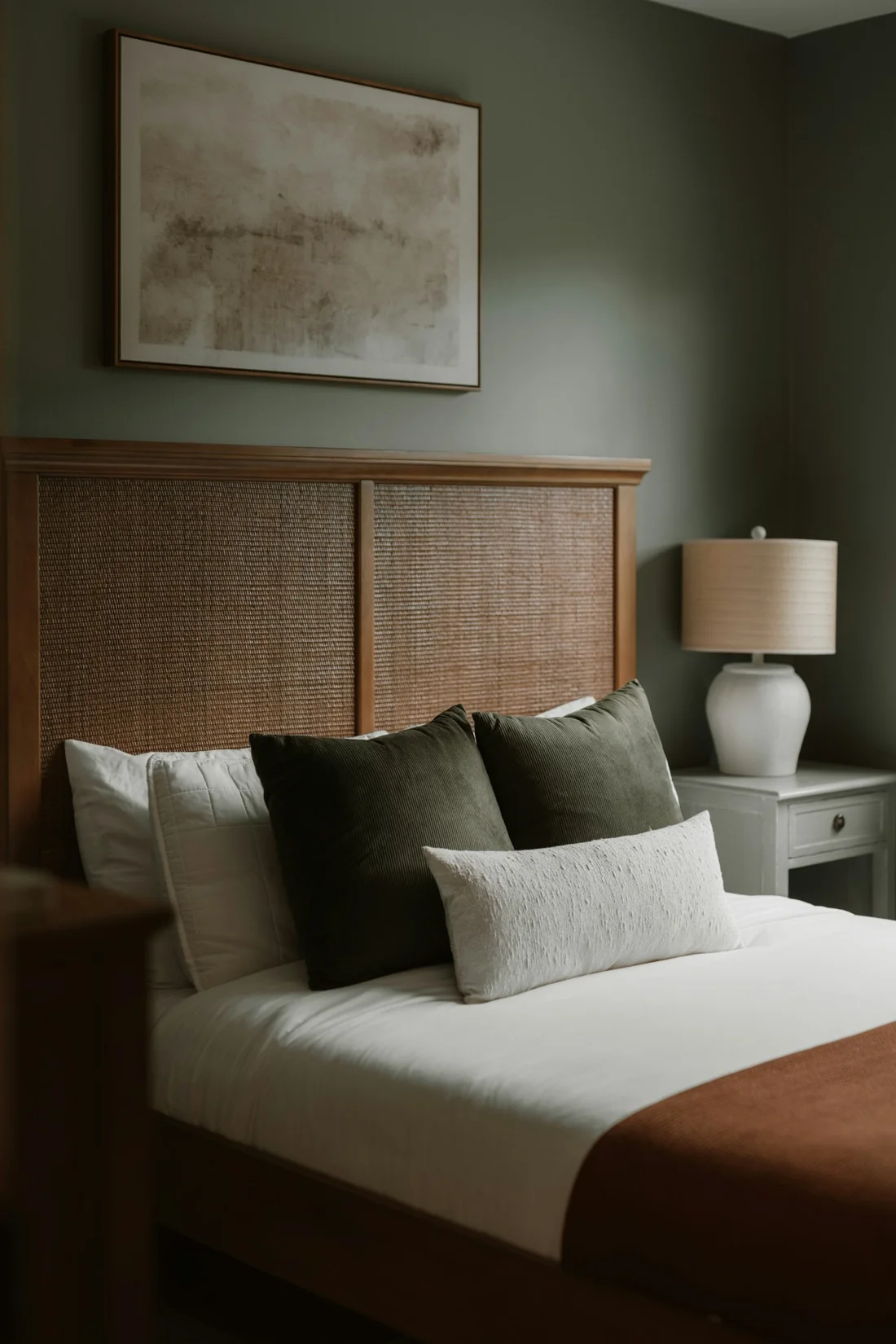 Layered pillows against a natural woven headboard